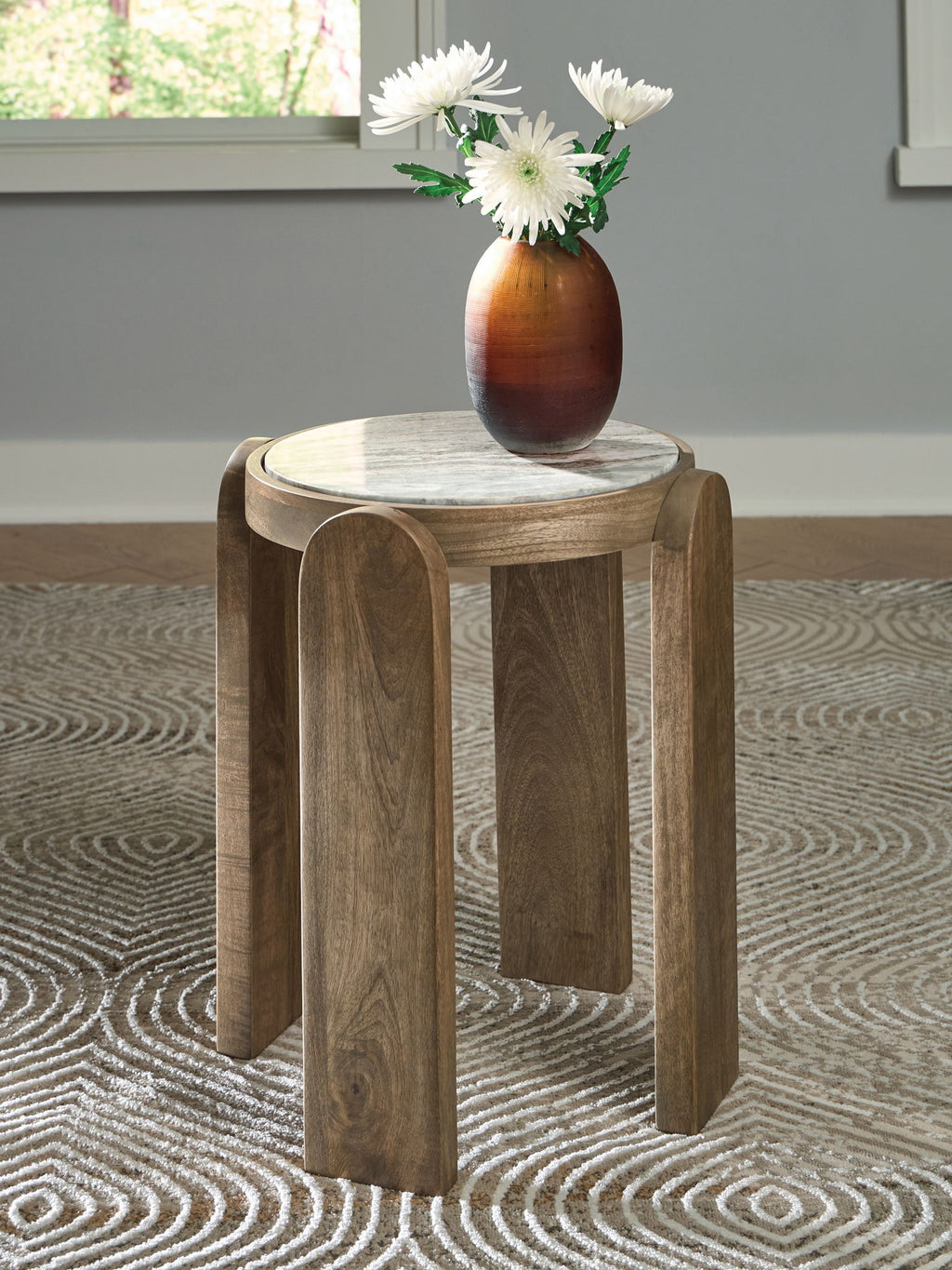 Round accent table with gray stone top and brown wood legs, with vase on top.