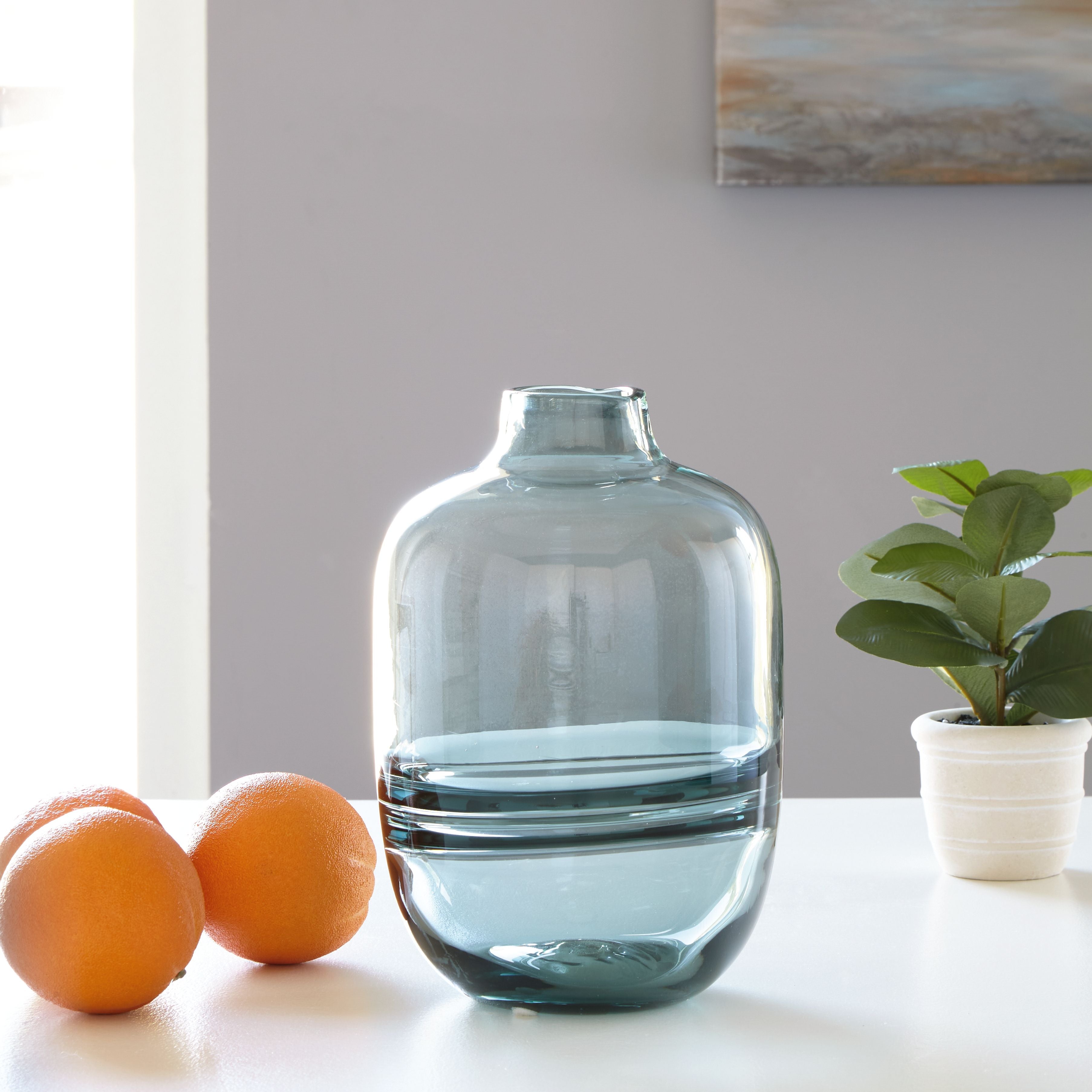 Teal glass vase with bulbous shape and narrow neck, glossy reflective surface.