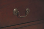 Nightstand drawer pull with curved metal U-handle on reddish brown wood