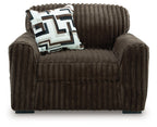 Dark brown chair and a half with geometric throw pillow on the seat