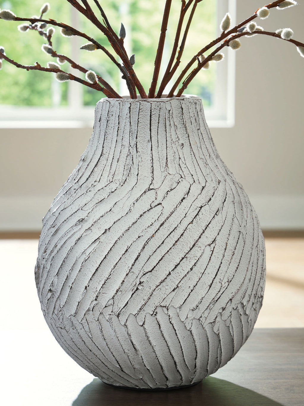 White vase with carved vertical stripe pattern holding decorative brown stems