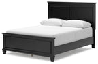 Black panel bed with one front storage drawer and a white upholstered mattress and pillows.