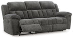 Reclining sofa in dark gray fabric with padded headrests and recline footrests