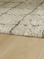 Beige shag rug corner, looped texture with faint grid lines