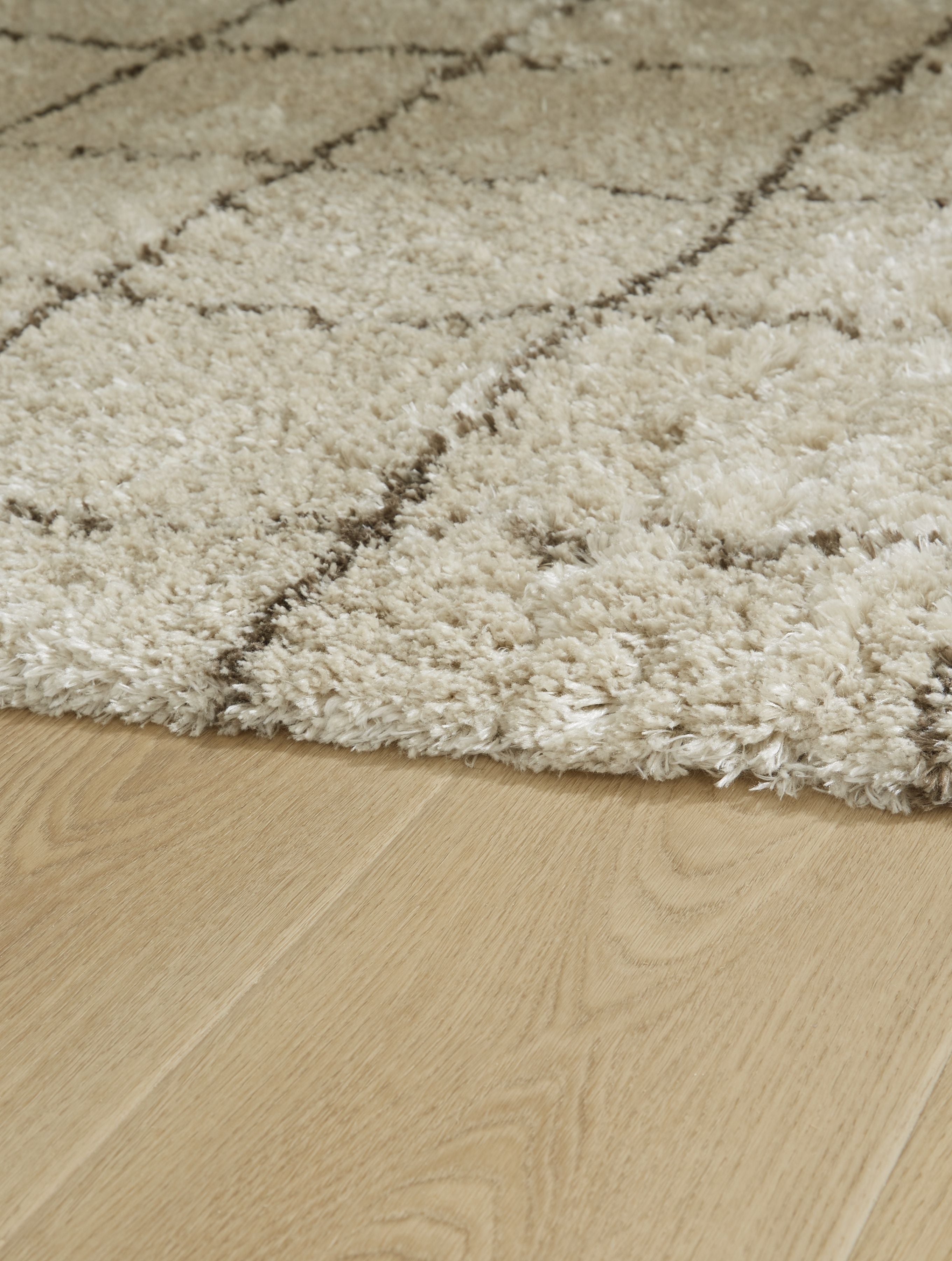 Beige shag rug corner, looped texture with faint grid lines
