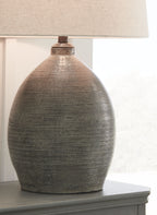 Textured gray table lamp base with beige fabric drum shade on side table