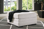 Stone oversized ottoman with gray fabric and black throw blanket on top