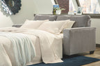 Slate sleeper sofa with extended mattress and white bedding and pillows
