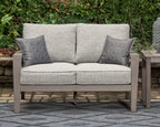 Gray loveseat with two square patterned throw pillows and twin seat cushions