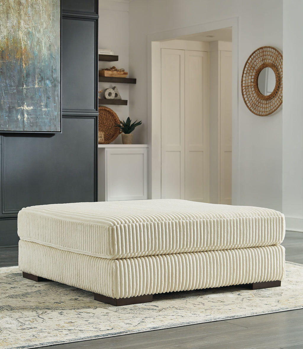 Beige oversized ottoman with ribbed fabric upholstery and rounded square cushion top