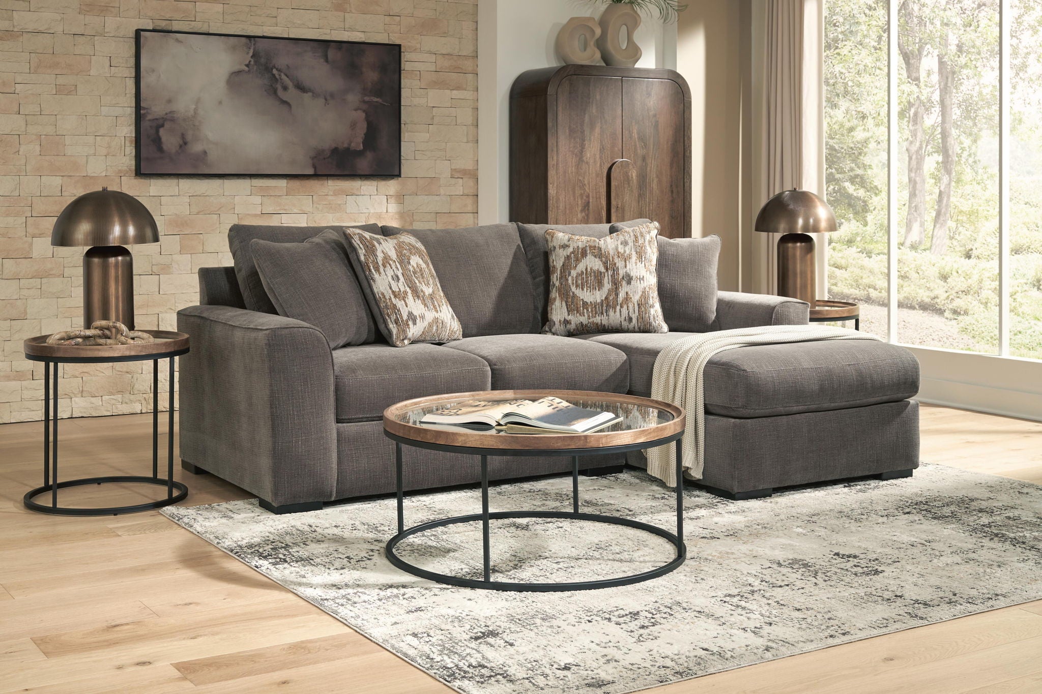 Gray sectional sofa with chaise and patterned pillows, styled with a round coffee table
