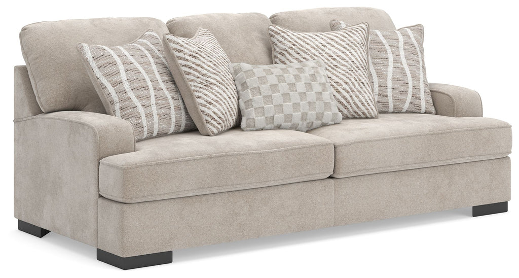 Taupe upholstered sofa with arms and four patterned throw pillows, striped and checkered