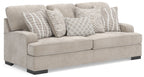 Taupe upholstered sofa with arms and four patterned throw pillows, striped and checkered