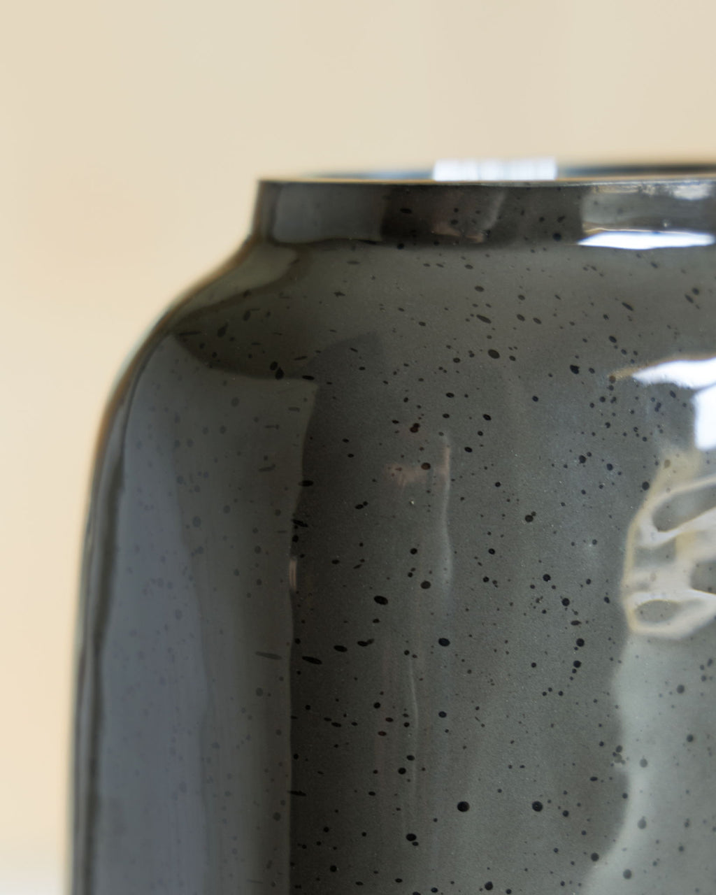 Close-up of dark speckled ceramic vase body with glossy reflections