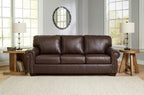 Dark brown upholstered sofa with tufted back cushions and nailhead trim