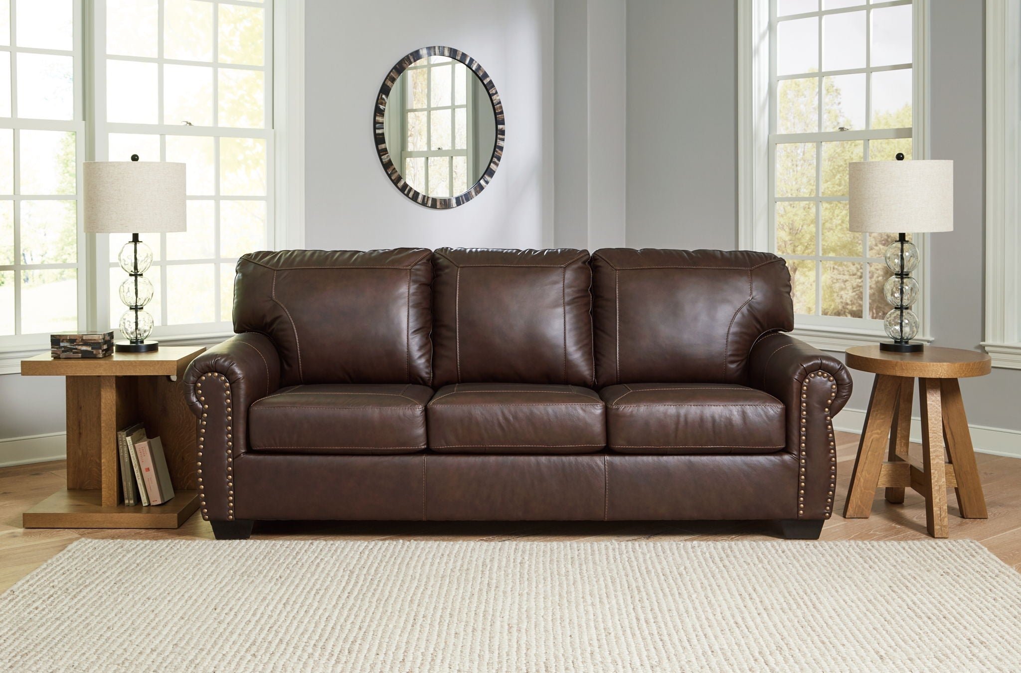 Dark brown upholstered sofa with tufted back cushions and nailhead trim