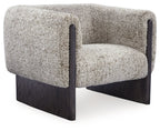Accent chair with oatmeal boucle upholstery, dark wood legs, and rounded armrests.