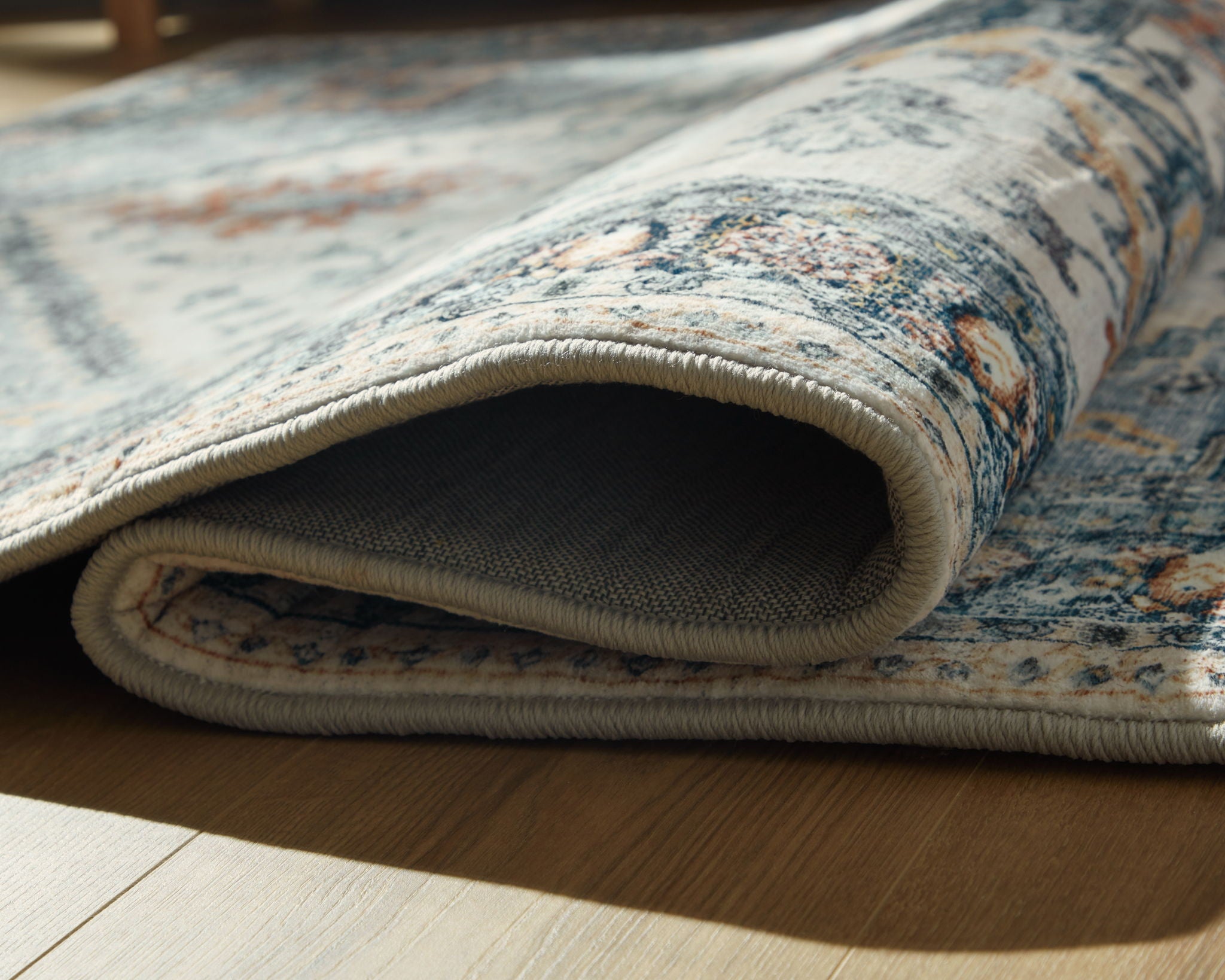 Wallney rug rolled edge detail, cream border stitching on blue patterned pile