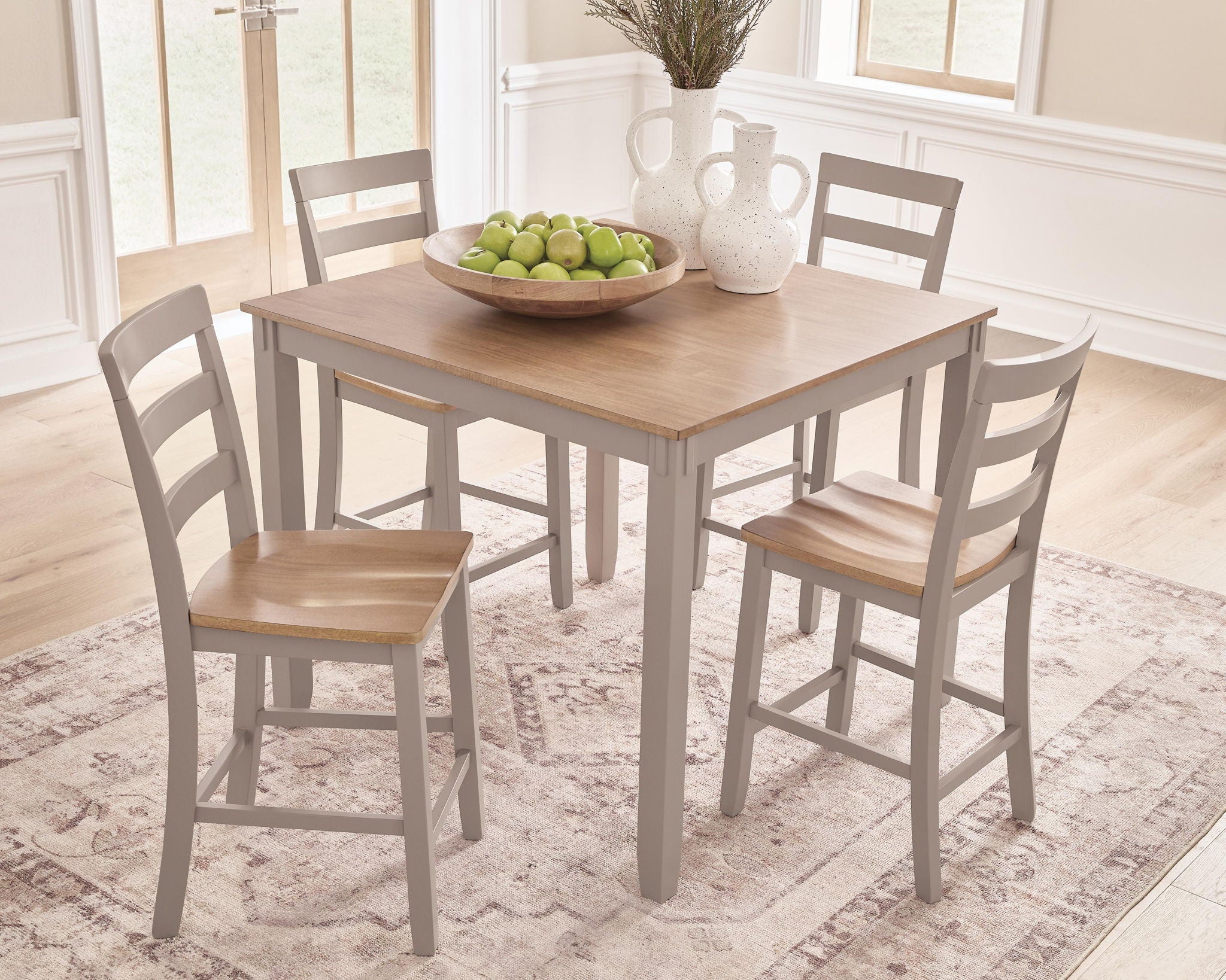 Square dining table with light wood top and two gray chairs beside it