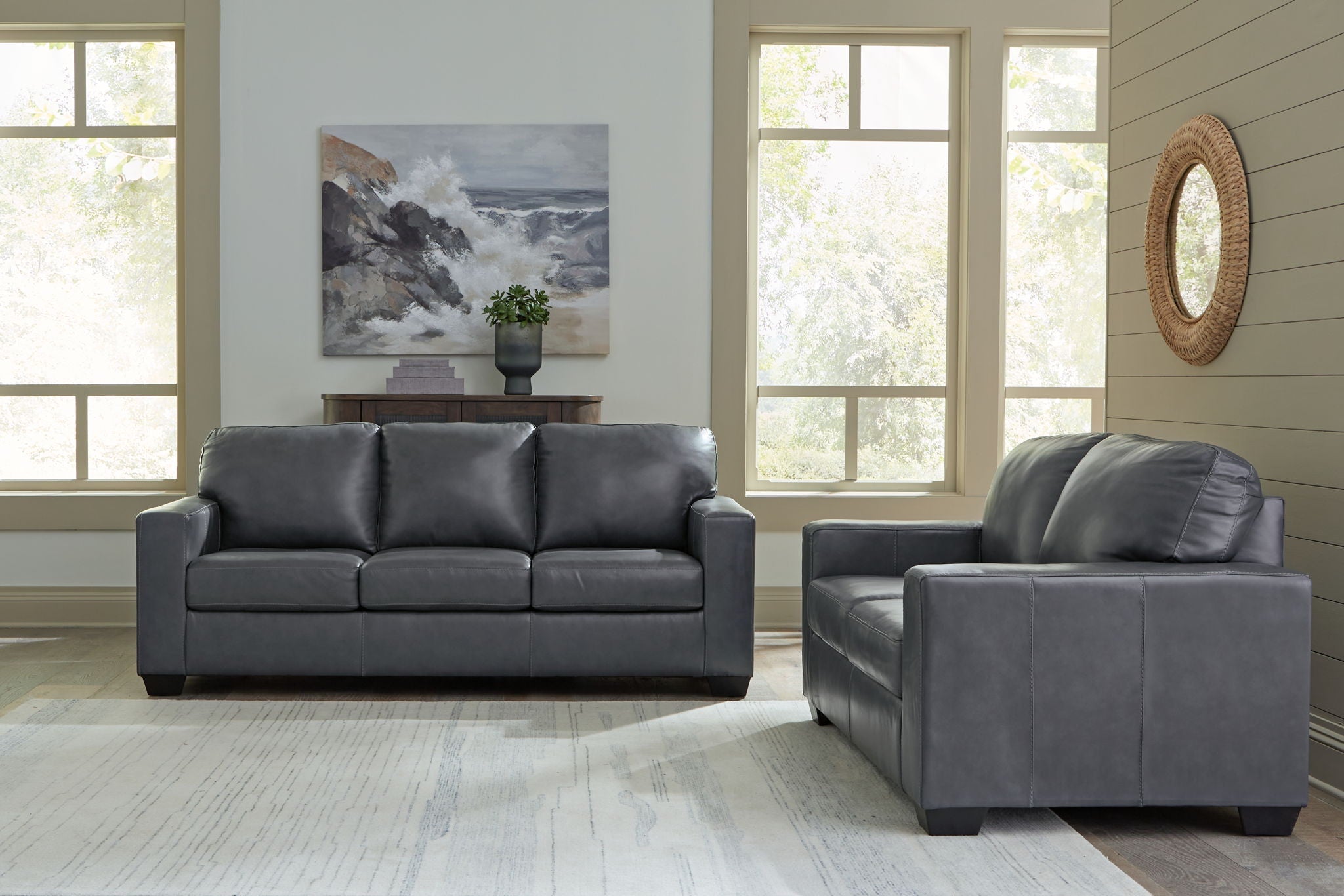 Dark gray leather sofa with three seat cushions and a matching armchair