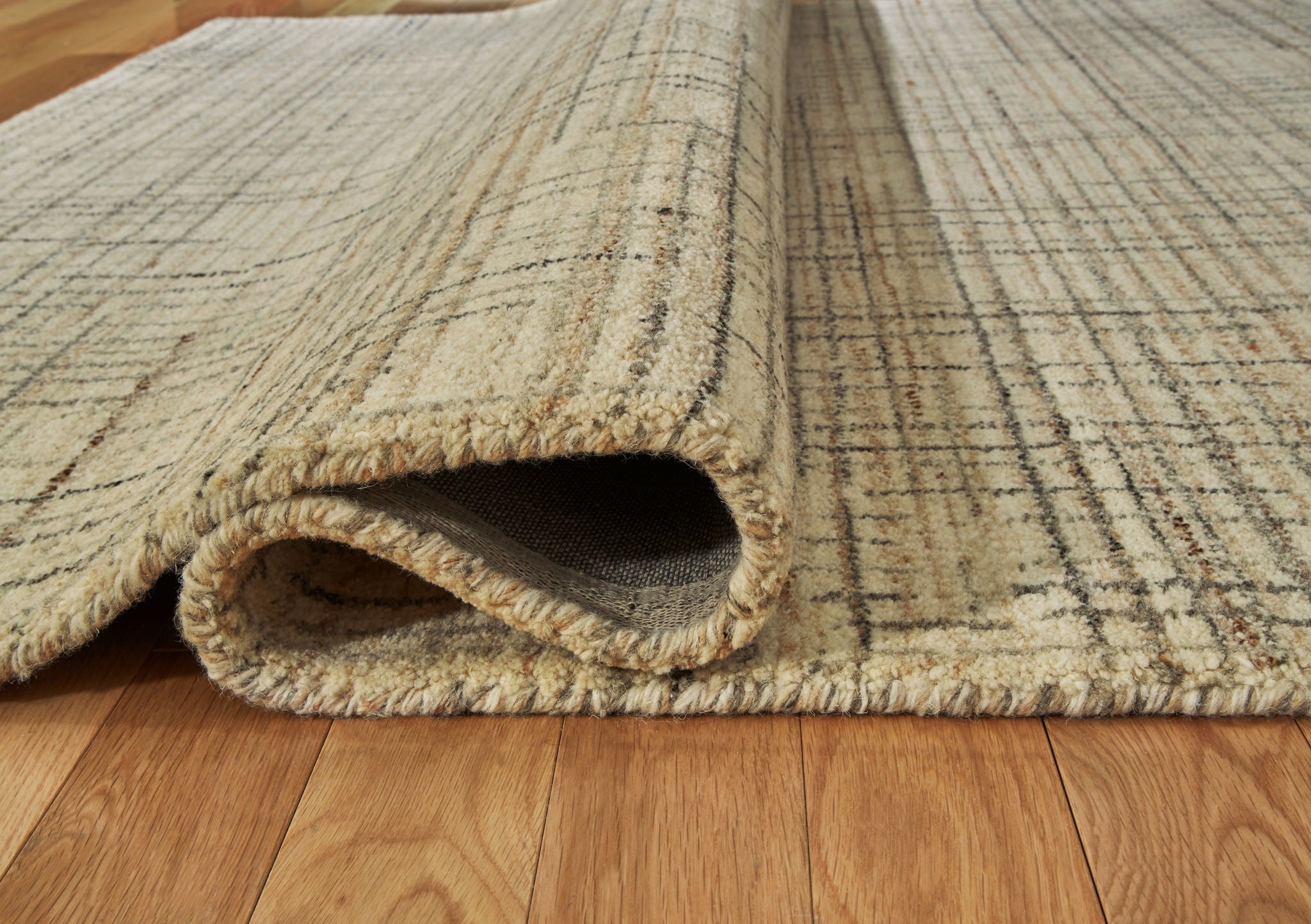 Ivory, gray, tan rug edge with folded underside showing low pile