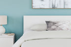 Panel headboard in light color with padded top and gray geometric accent pillows