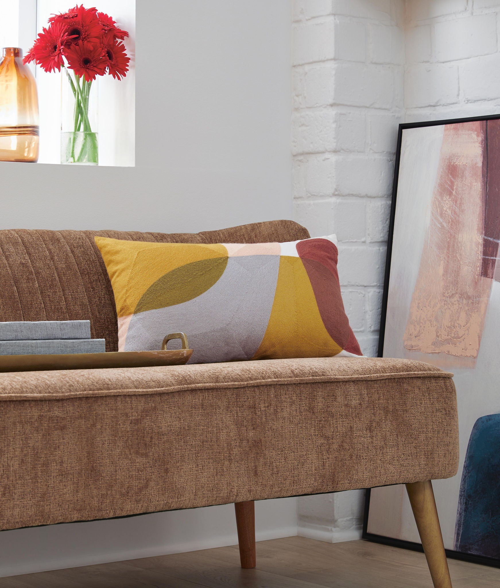 Geometric patchwork pillow on bed, yellow gray white and rust red