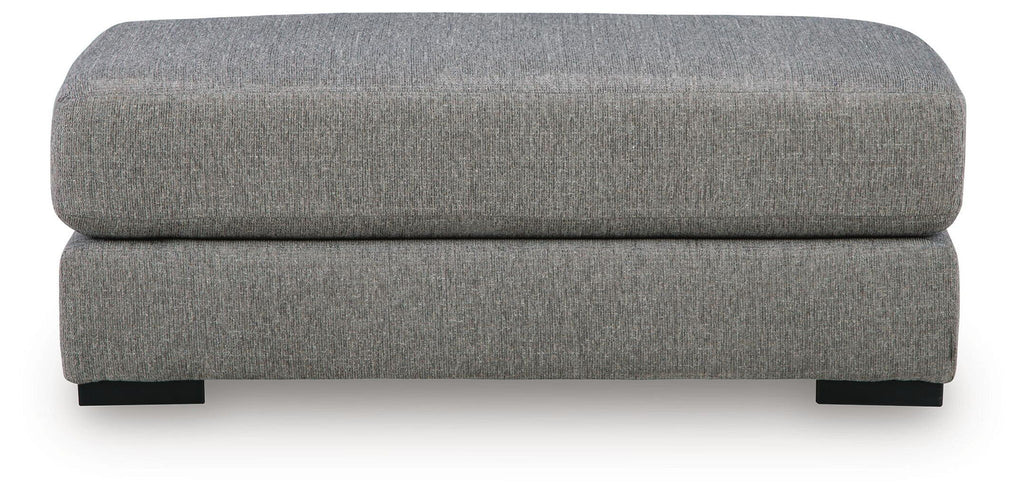 Grey upholstered ottoman with rounded top cushion and straight front profile, black legs