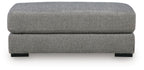 Grey upholstered ottoman with rounded top cushion and straight front profile, black legs