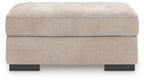 Taupe upholstered ottoman with low rectangular sides and black legs