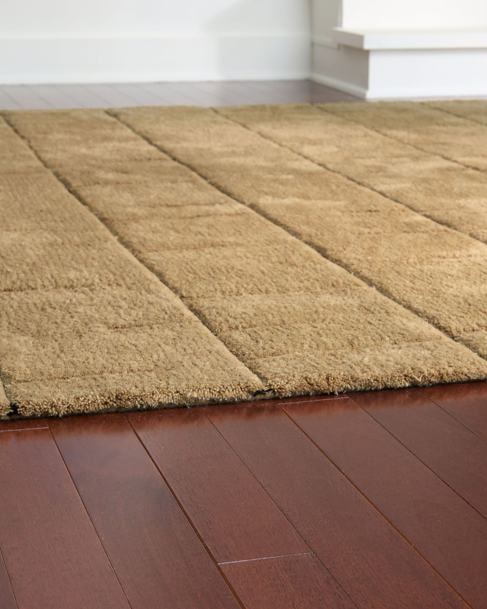 Light brown rug close-up, plush texture with stitched stripe-like sections