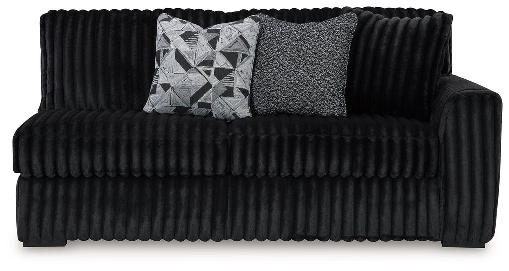 Dark velvet sofa with tufted front, rounded arms, and two throw cushions