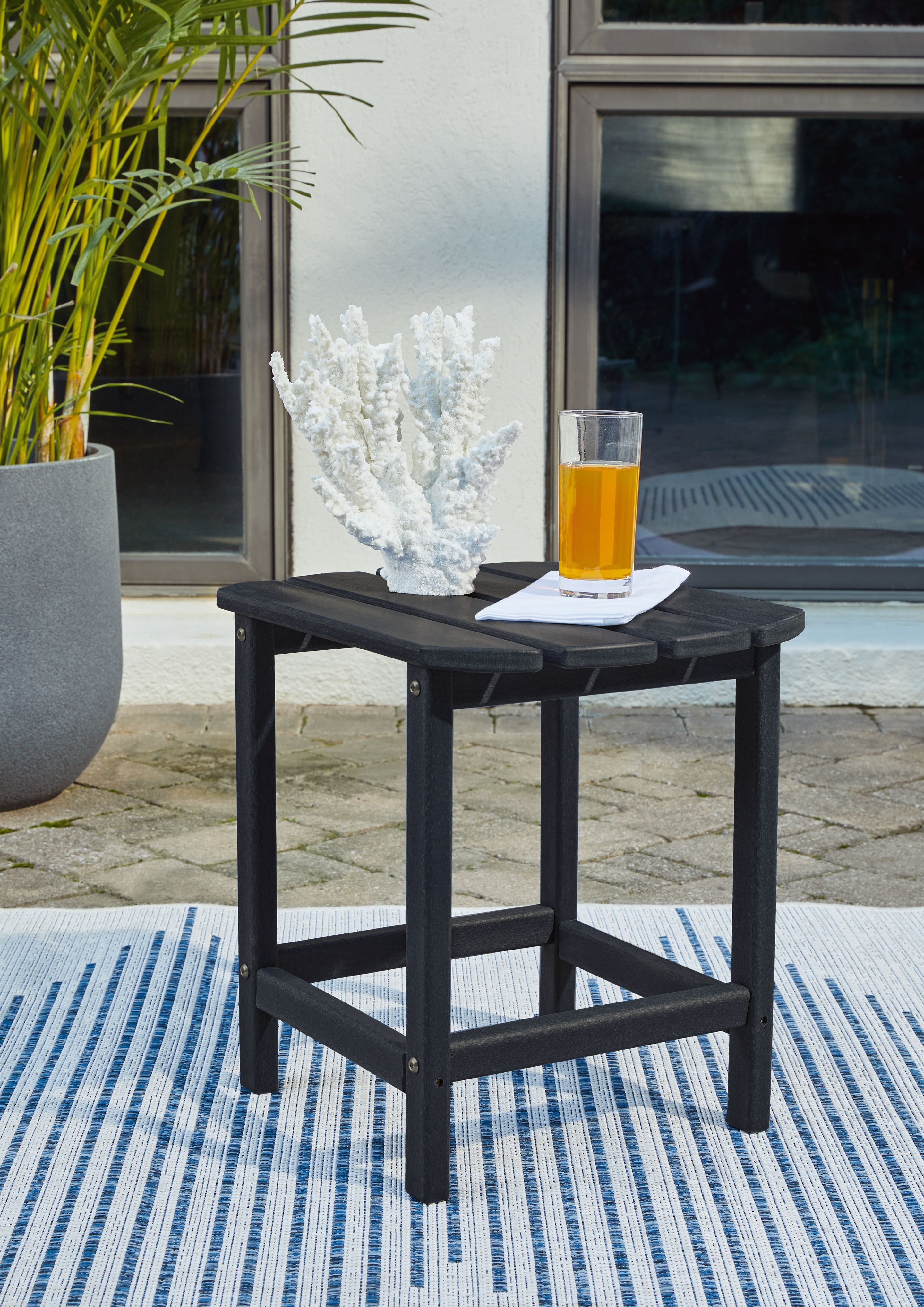 Outdoor end table in black with slatted top and open lower shelf