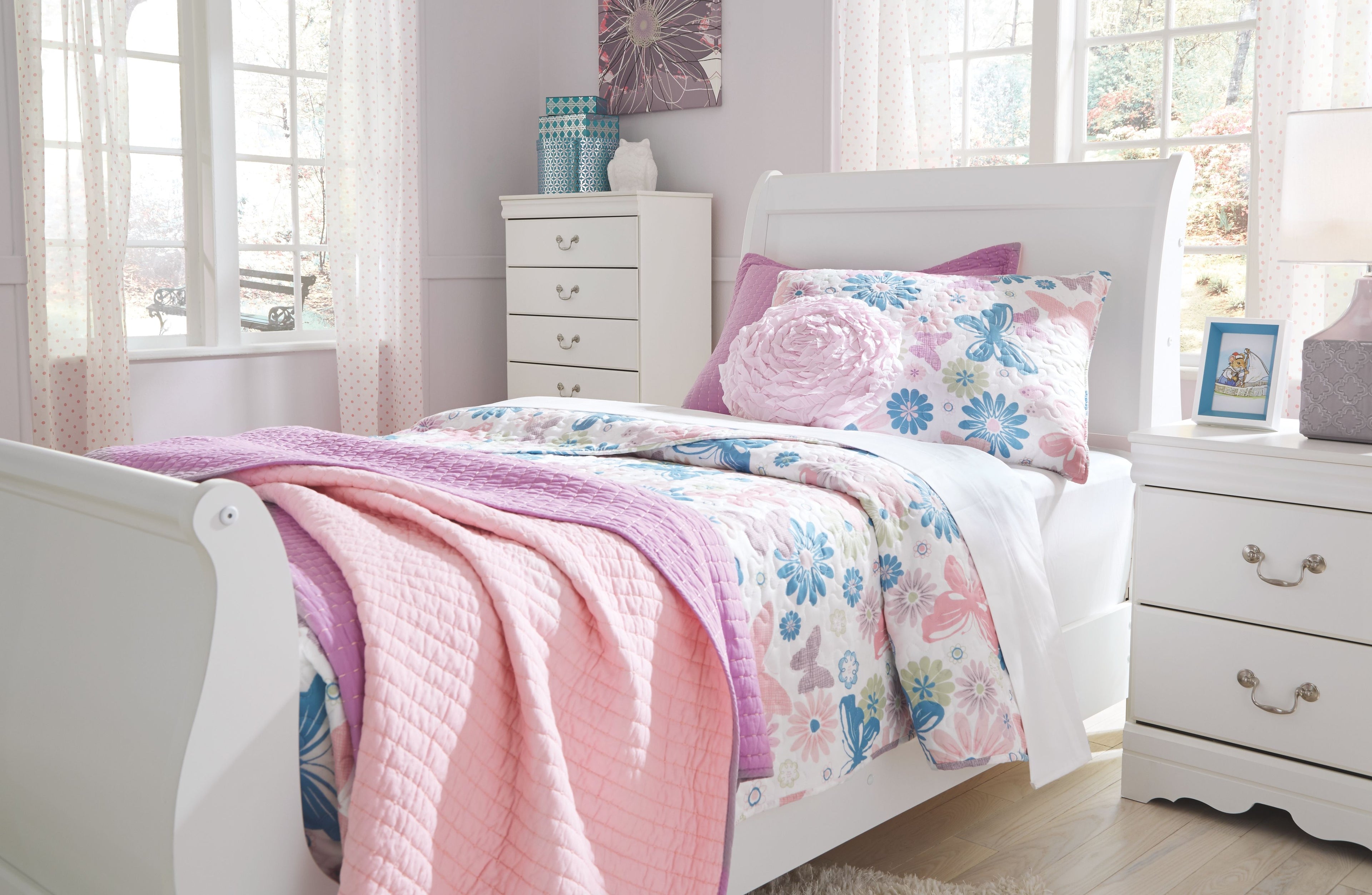 White sleigh bed headboard with curved posts and floral quilted bedding