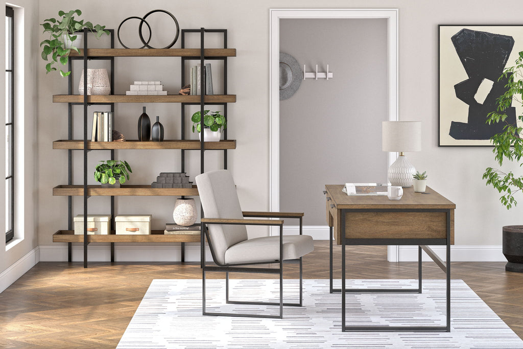 Home office set with light brown desk, bookcase shelving, and upholstered chair with black frame.