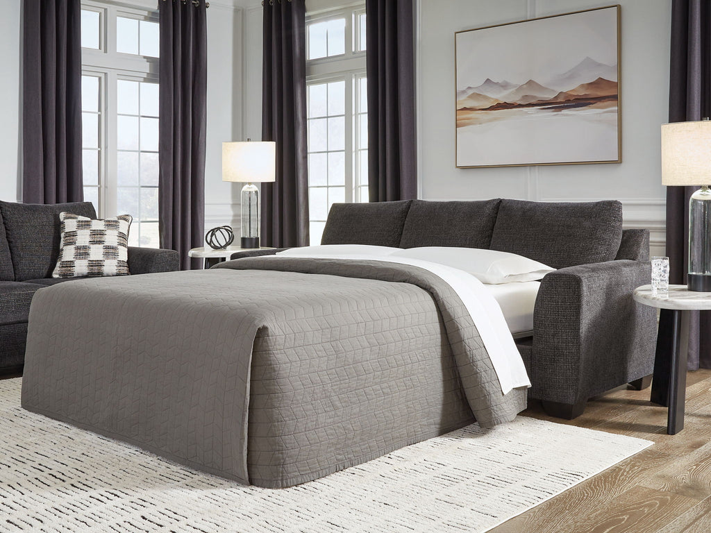 Sofa sleeper with bed extended, gray upholstery and dark throw pillows.