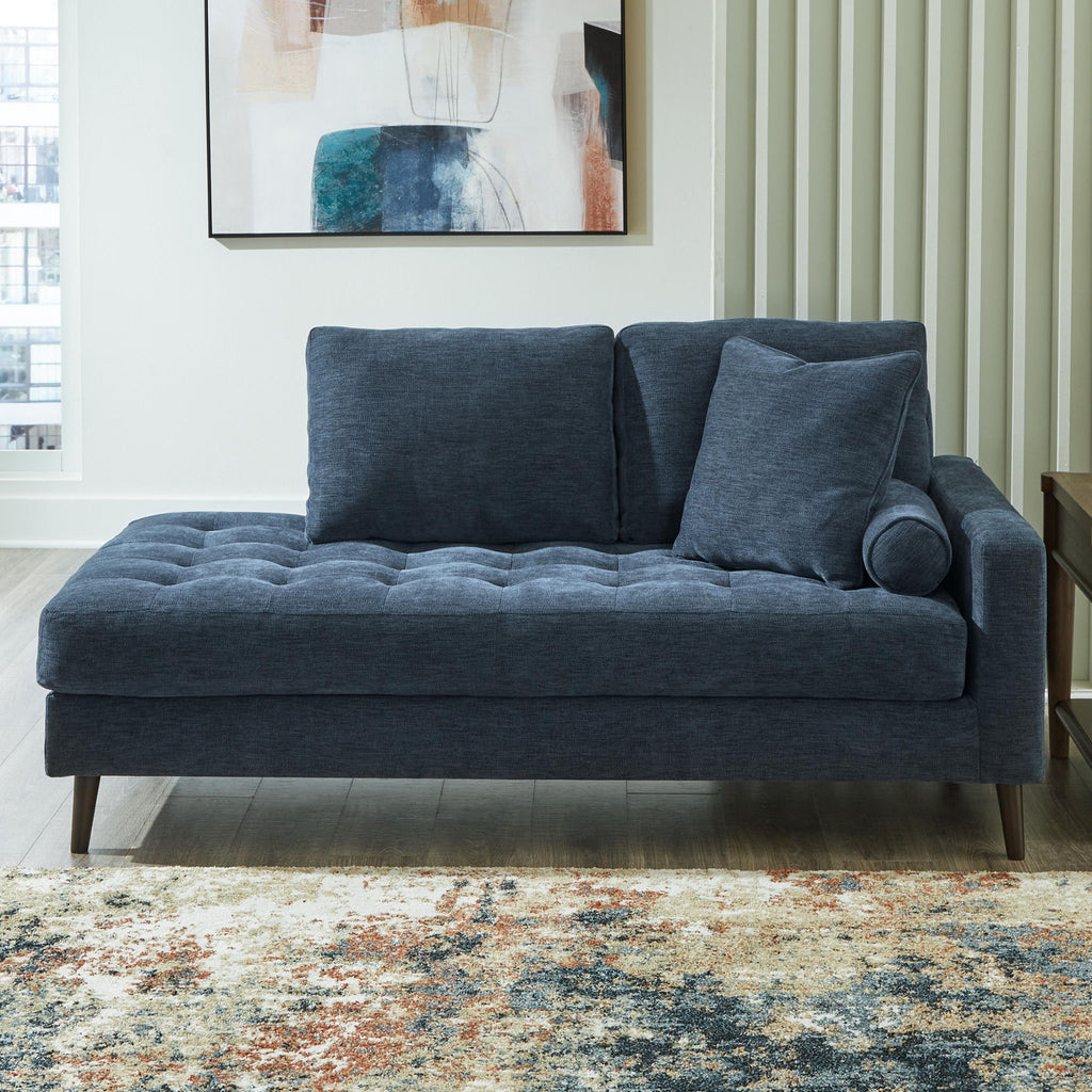 Blue fabric corner chaise with tufted seat and rounded bolster pillow