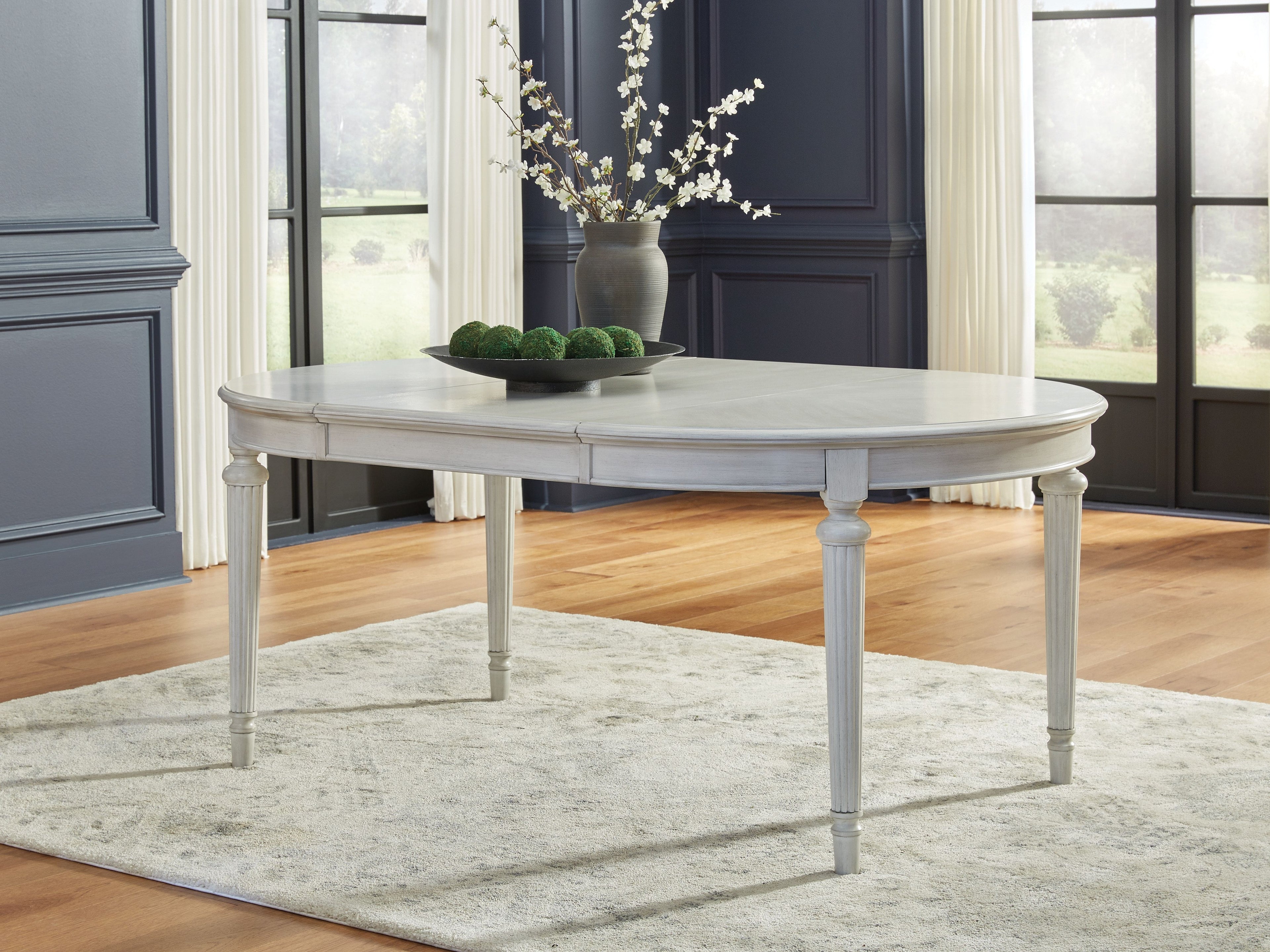 Antique white oval extension dining table with straight skirt and turned legs