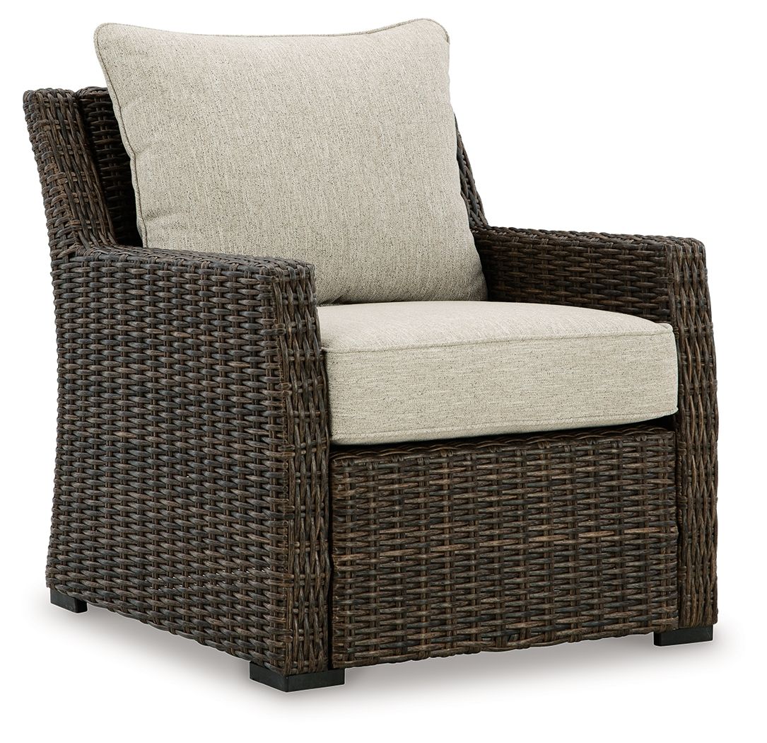 Brown wicker lounge chair with light beige seat cushion and tall back cushion