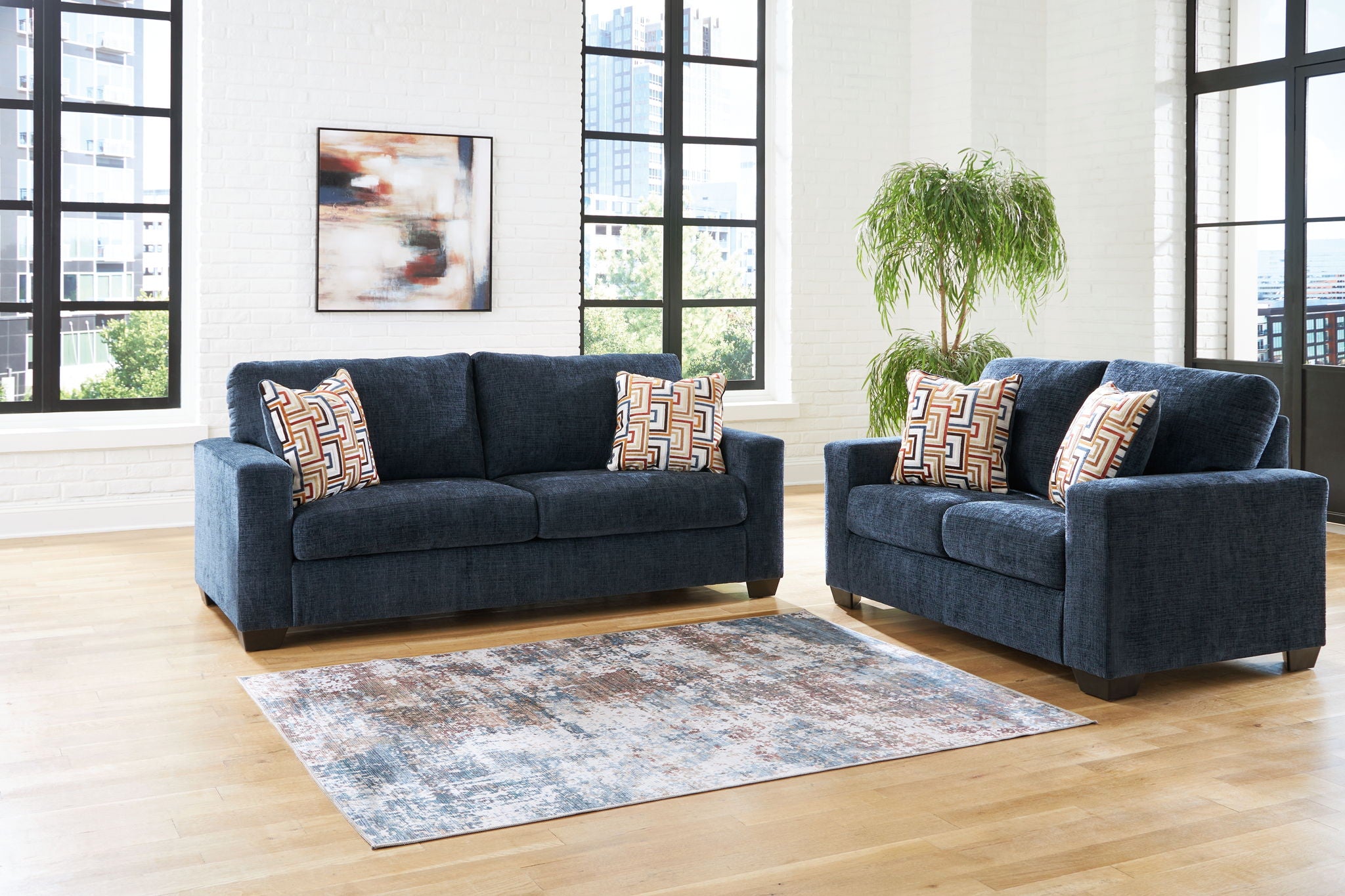 Blue living room sofa set with sofa, loveseat, and patterned geometric throw pillows.