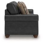 Dark gray sofa with two seat cushions and patterned throw pillows, side view