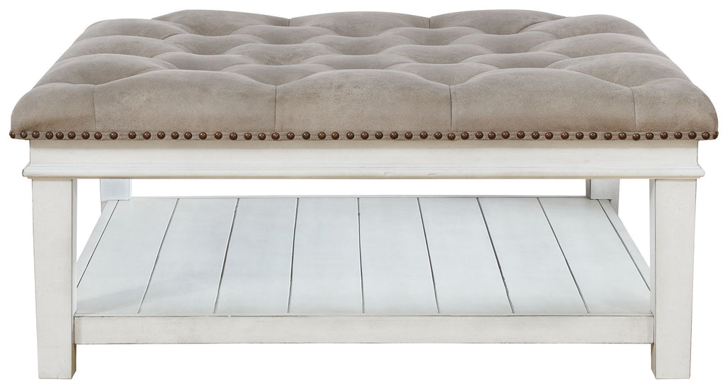Upholstered ottoman cocktail table with tufted top, nailhead trim, open shelf