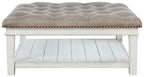 Upholstered ottoman cocktail table with tufted top, nailhead trim, open shelf