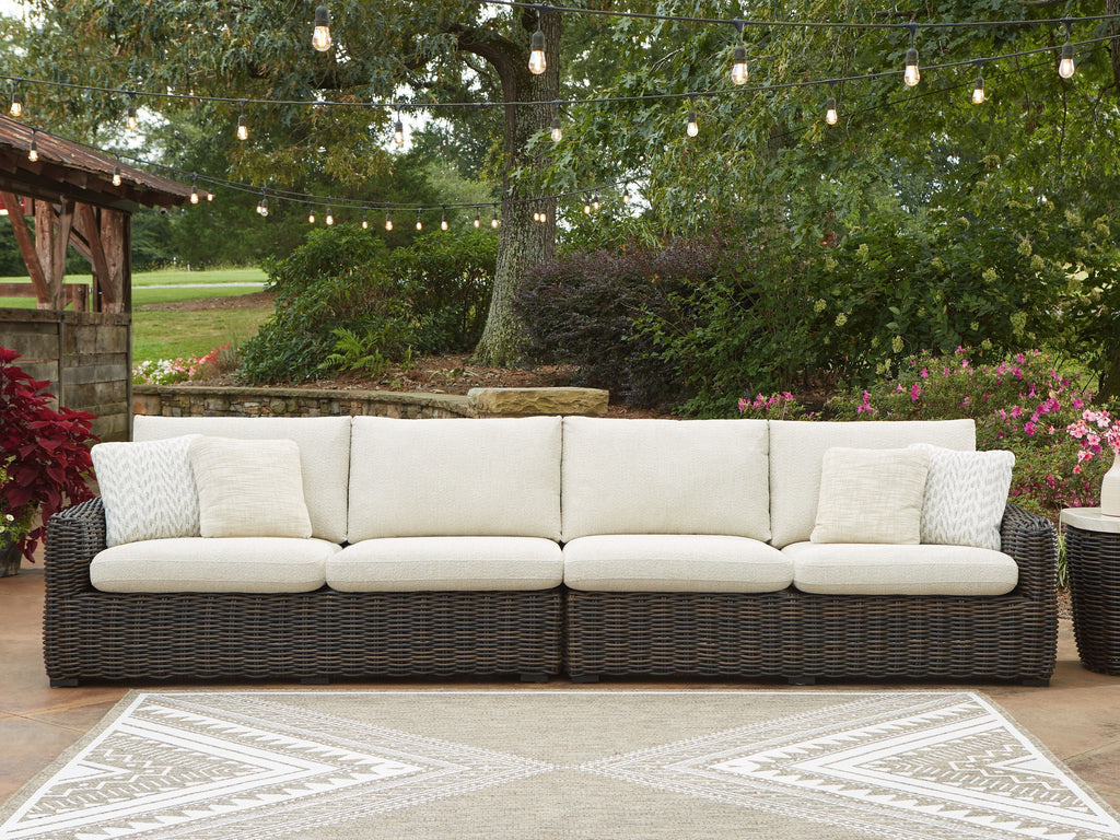 Outdoor dark brown wicker loveseat with beige cushions and patterned throw pillows