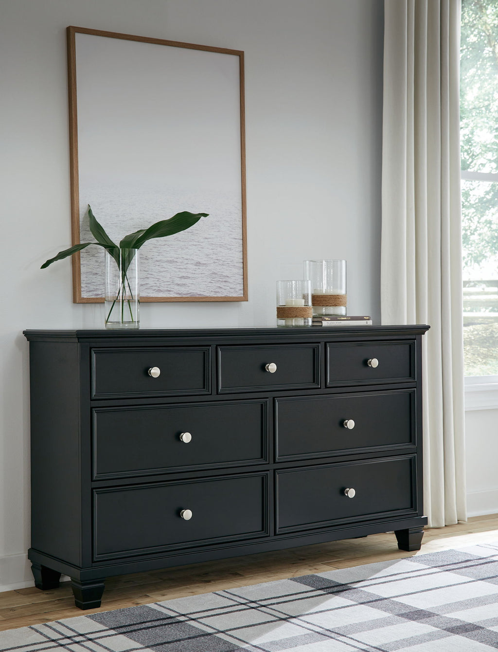 Black dresser with six drawers and round knobs, topped with a wall mirror