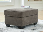 Dark gray upholstered ottoman with cushioned lid and dark block legs