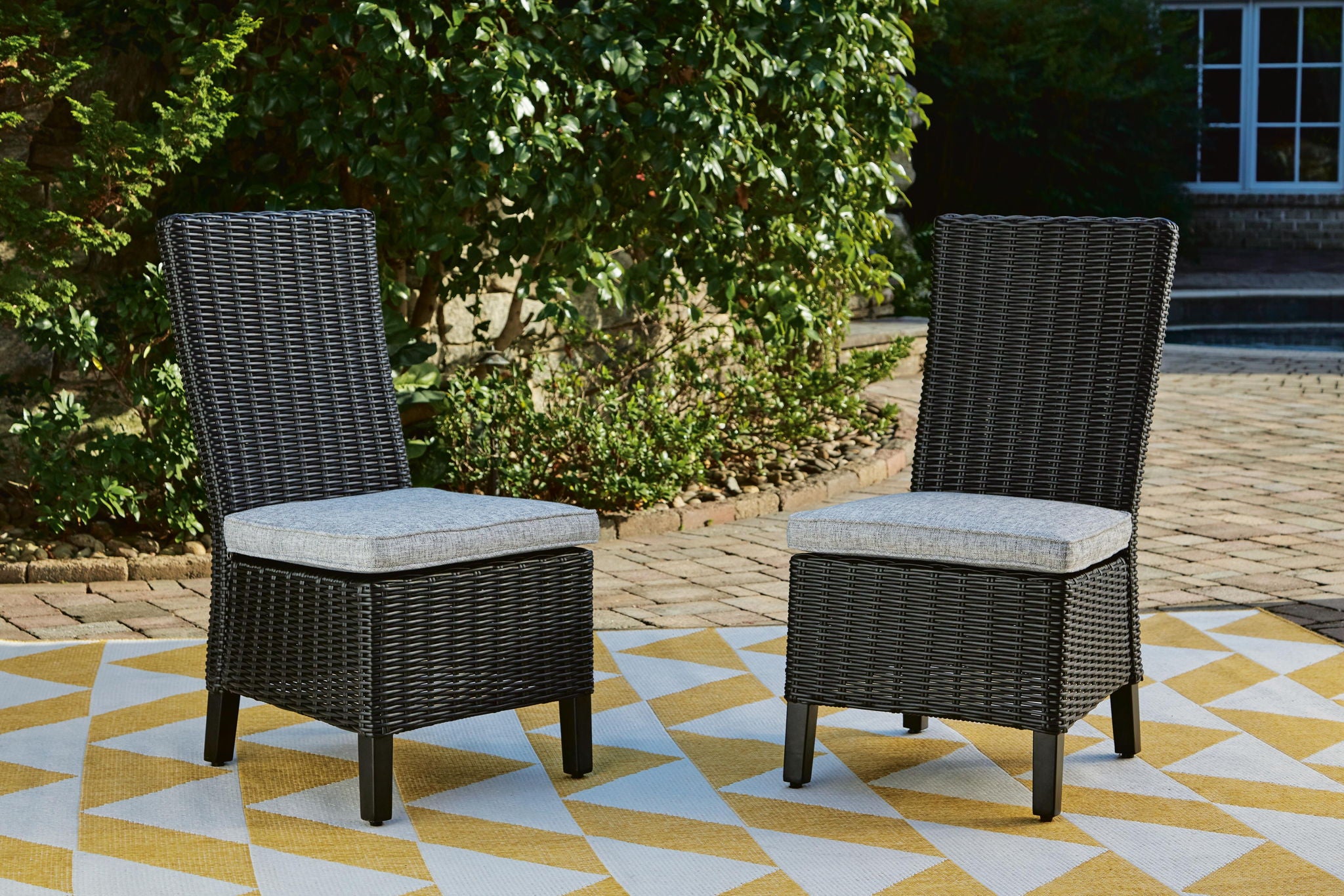 Set of 2 black outdoor dining side chairs with woven backs and light gray seat cushions