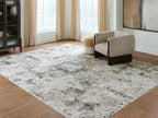 Large distressed gray-and-beige area rug with abstract pattern under seating in room.