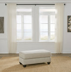 Upholstered ottoman in fog beige with square padded top and dark legs