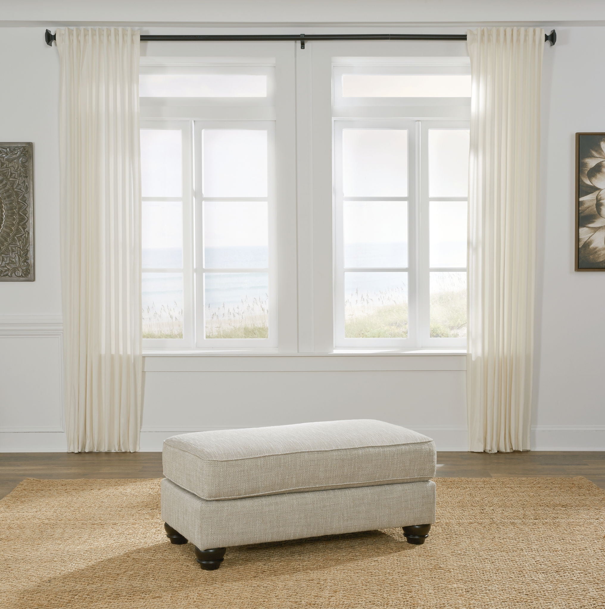 Upholstered ottoman in fog beige with square padded top and dark legs